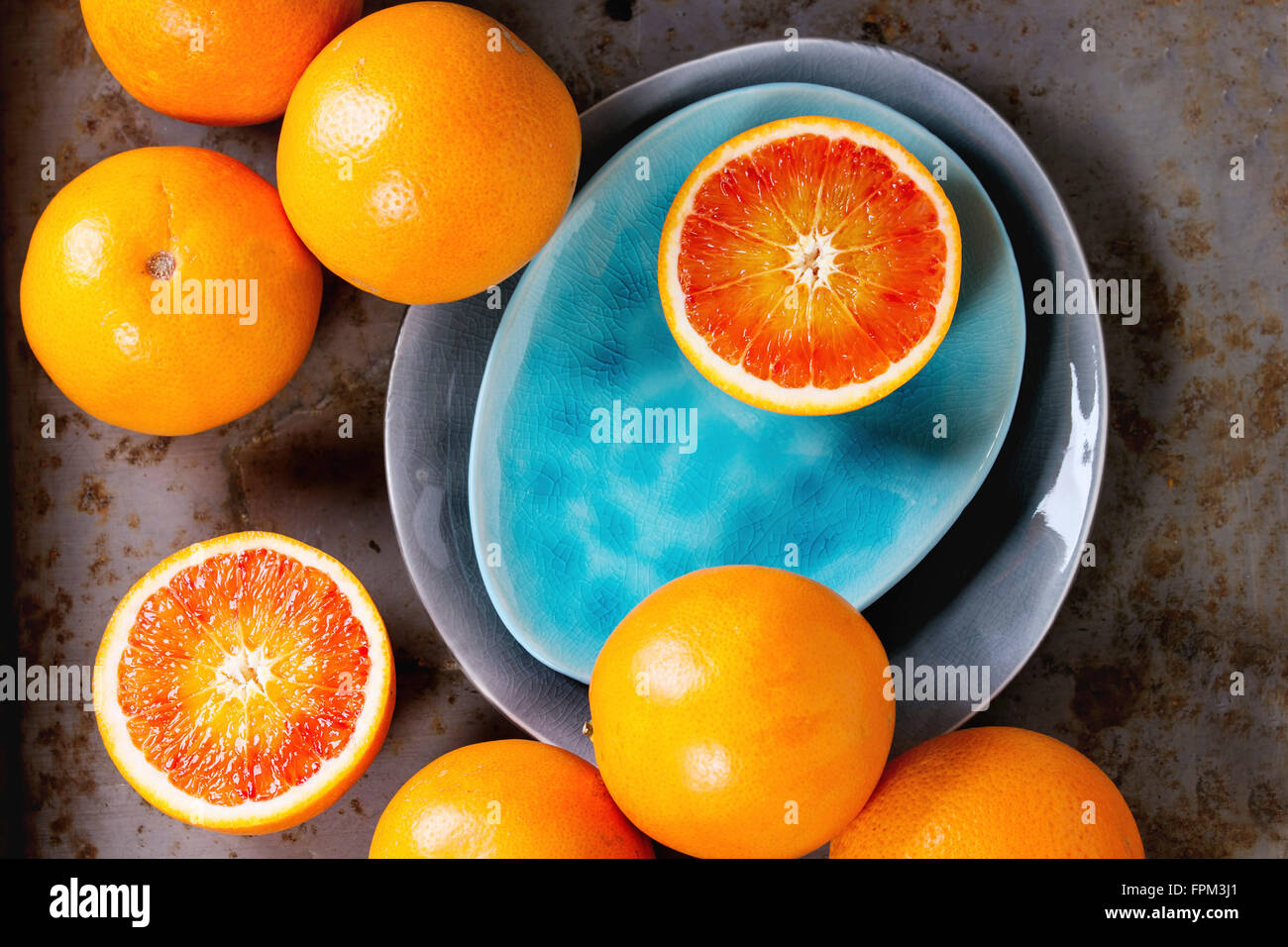 Tout en tranches et l'orange sanguine sicilienne sur fruits et turquoises ou plaques en céramique gris sur fond de métal rouillé. Mise à plat Banque D'Images