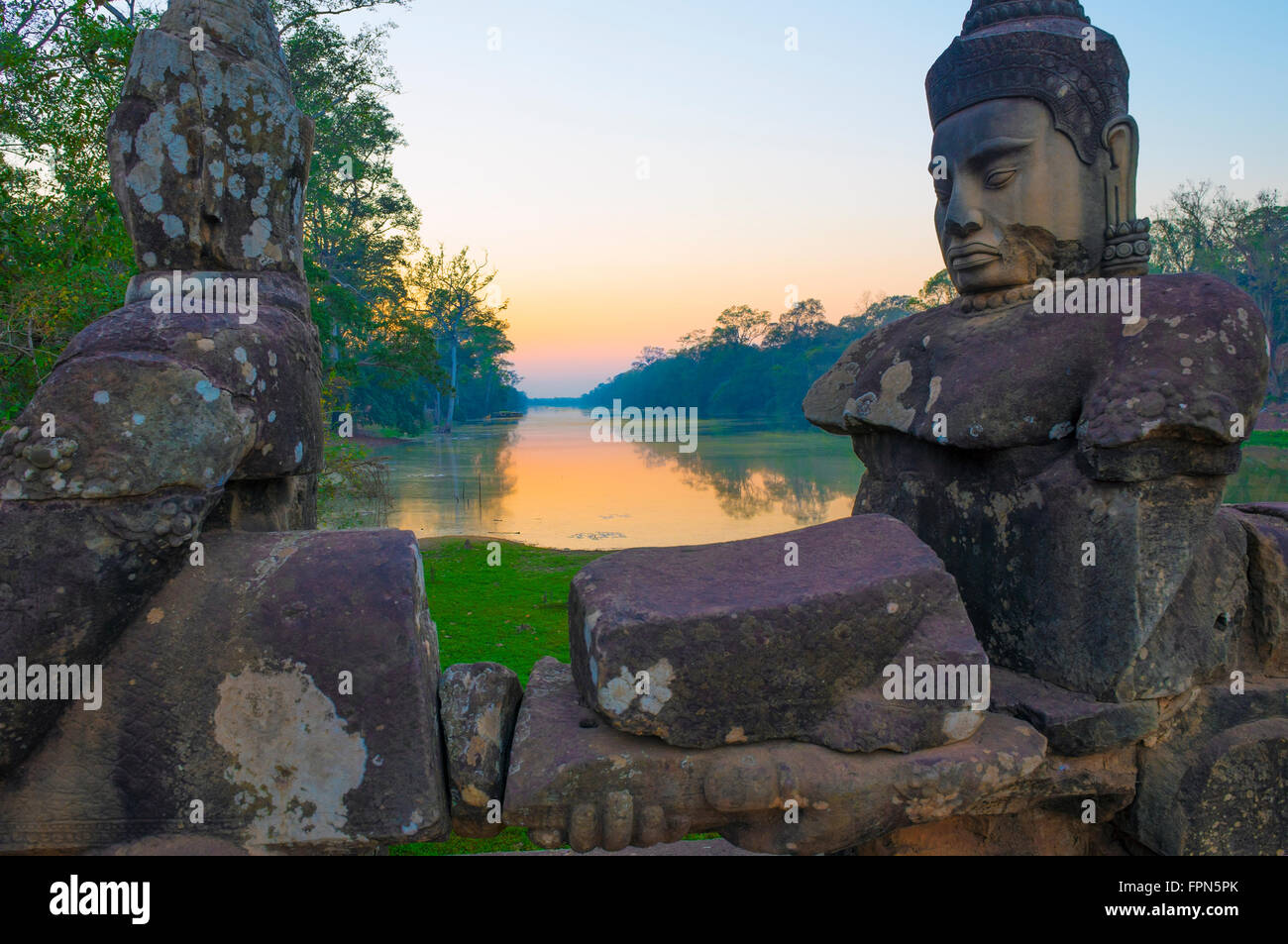 Coucher du soleil sur le pont-jetée à la Porte Sud d'Angkor Thom avec les dieux et les démons tirant sur un serpent géant menant à la ville construit Banque D'Images