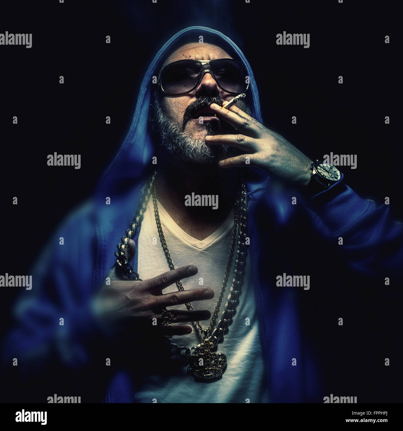 Portrait d'un homme plus âgé, fumer un cigare, le port de colliers d'or et bleu. Le hip-hop et urbain. Banque D'Images