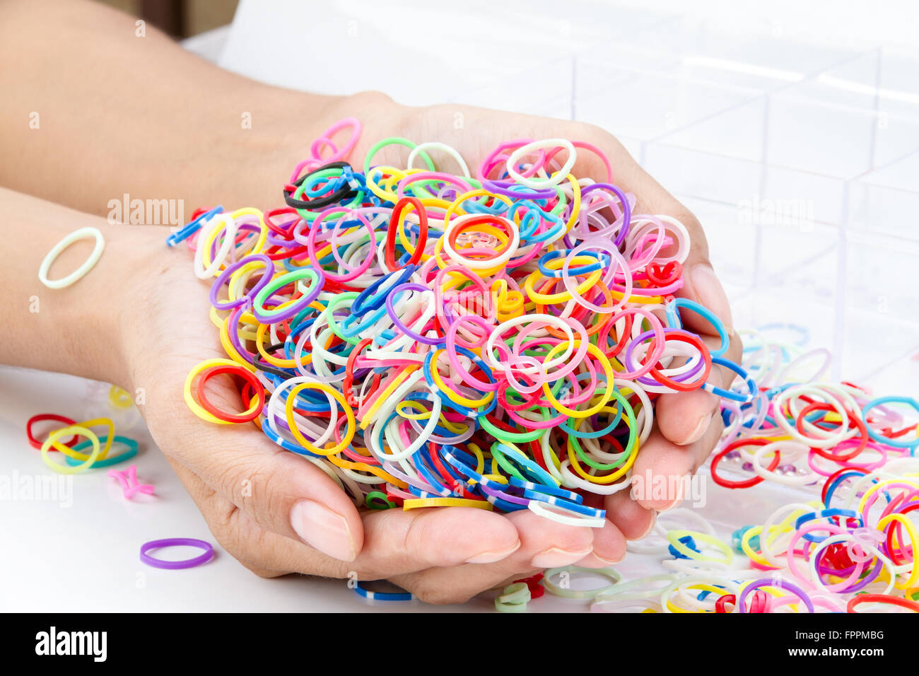 Les mains et les tas de petites bandes de caoutchouc coloré couleur  arc-en-ciel arc-en-ciel pour faire des bracelets à tisser sur la table  Photo Stock - Alamy