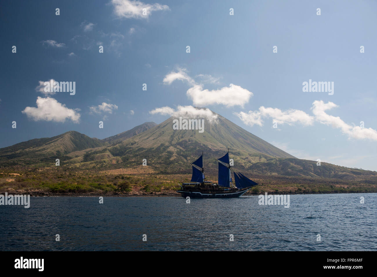 Une goélette pinisi indonésien Pulau Sangeang près de voiles, une île volcanique à distance près de Komodo en Indonésie. Banque D'Images