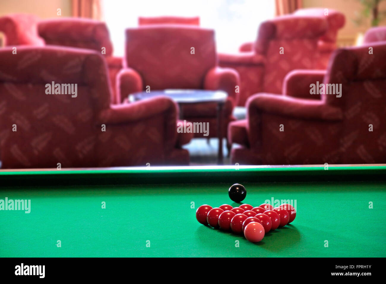 Boules de billard rouge sur une table de billard avec des chaises rouges à l'arrière-plan Banque D'Images