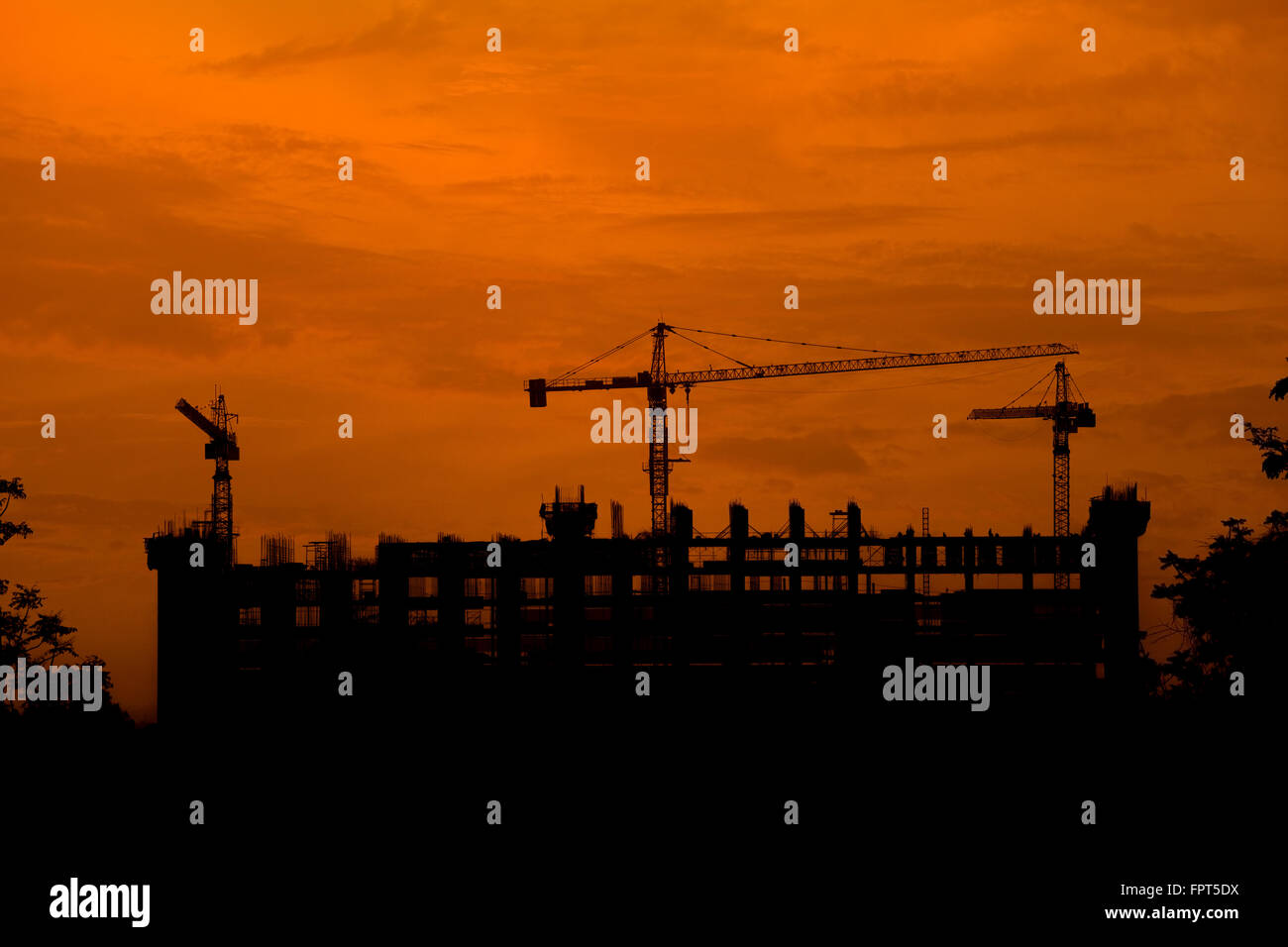 Silhouette de grue a tour sur un chantier de construction au coucher du soleil Banque D'Images