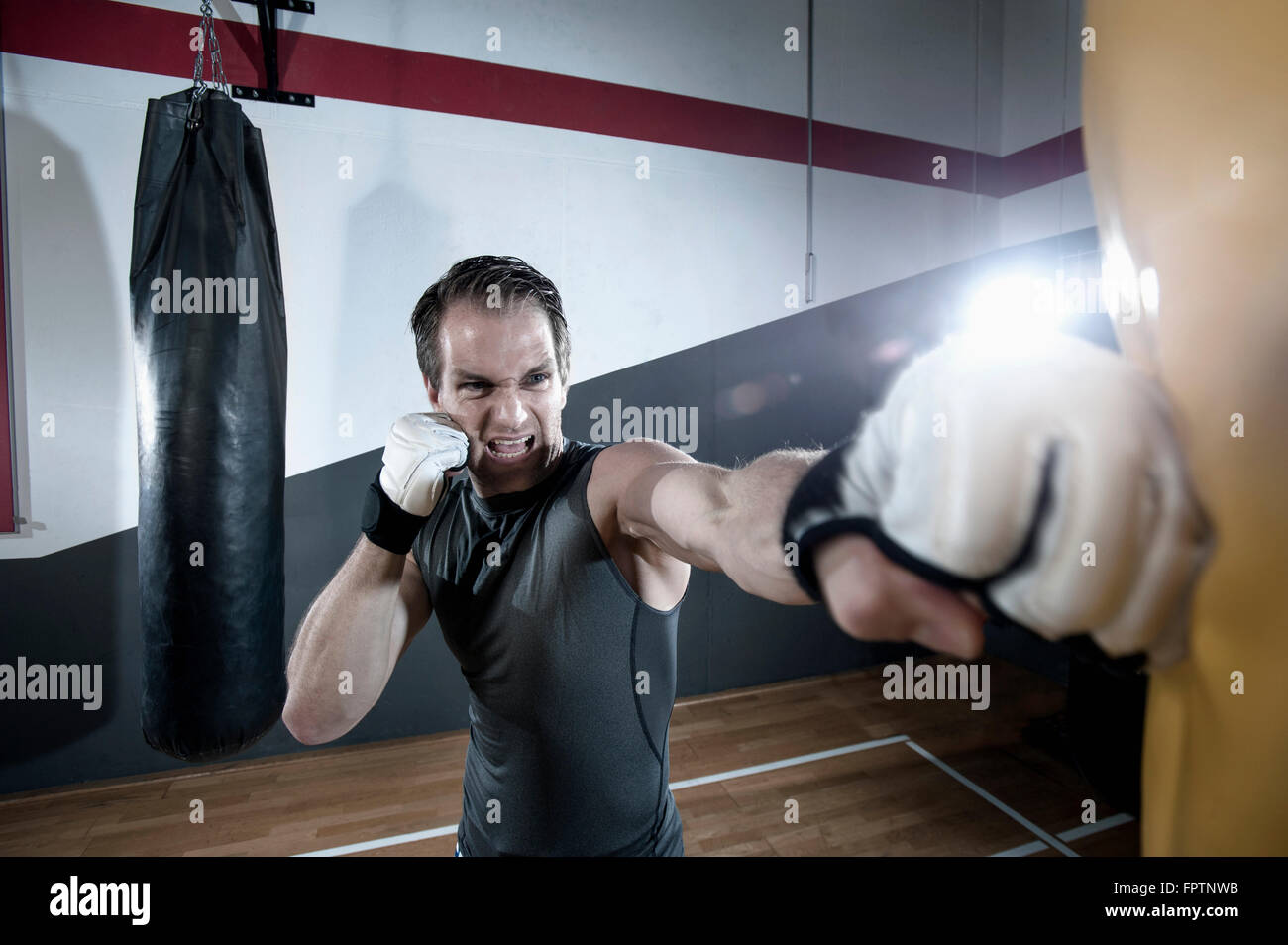 Sportsman faisant la formation de force en enfonçant le sac dans la salle de sport, Bavière, Allemagne Banque D'Images