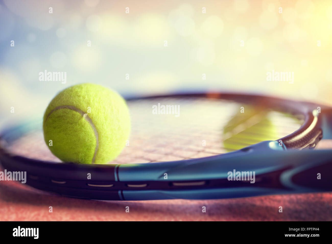 Balle de tennis reposant sur une raquette de tennis sur un cour d'asphalte rouge Banque D'Images