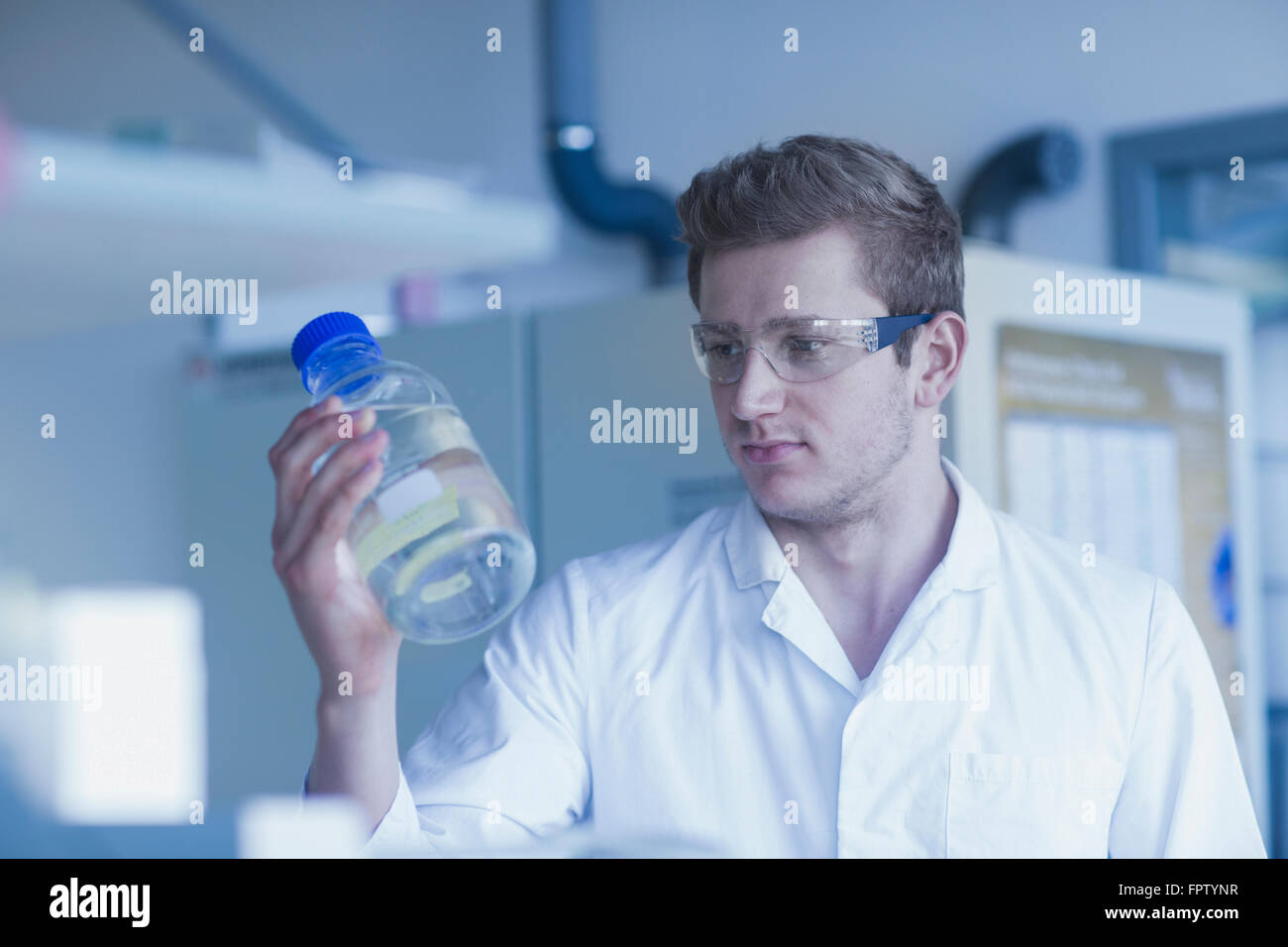 Young male scientist holding bouteille liquide dans un laboratoire, Freiburg im Breisgau, Bade-Wurtemberg, Allemagne Banque D'Images