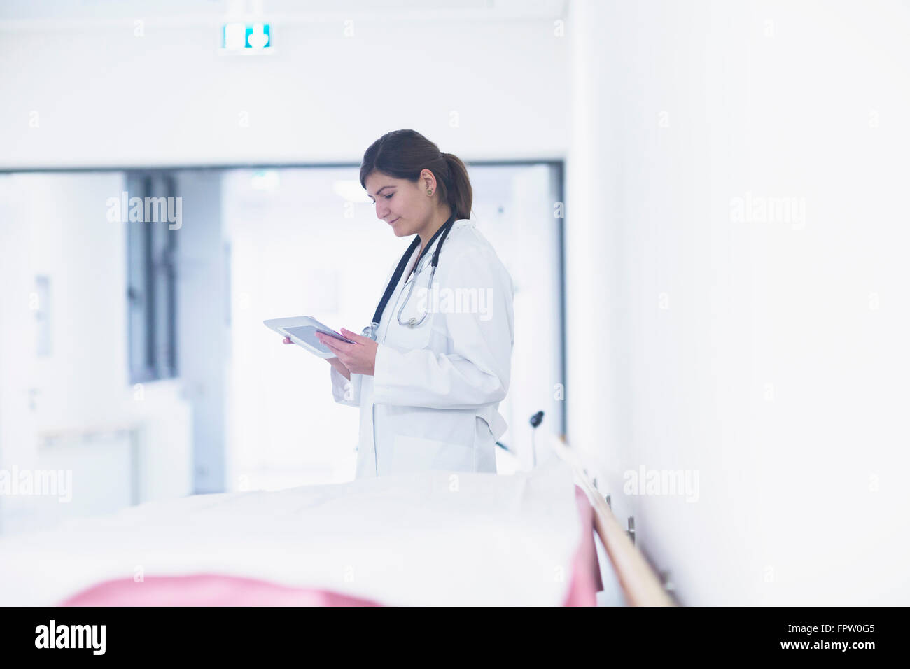 Jeune femme médecin à l'aide d'une tablette numérique à l'hôpital, Freiburg im Breisgau, Bade-Wurtemberg, Allemagne Banque D'Images