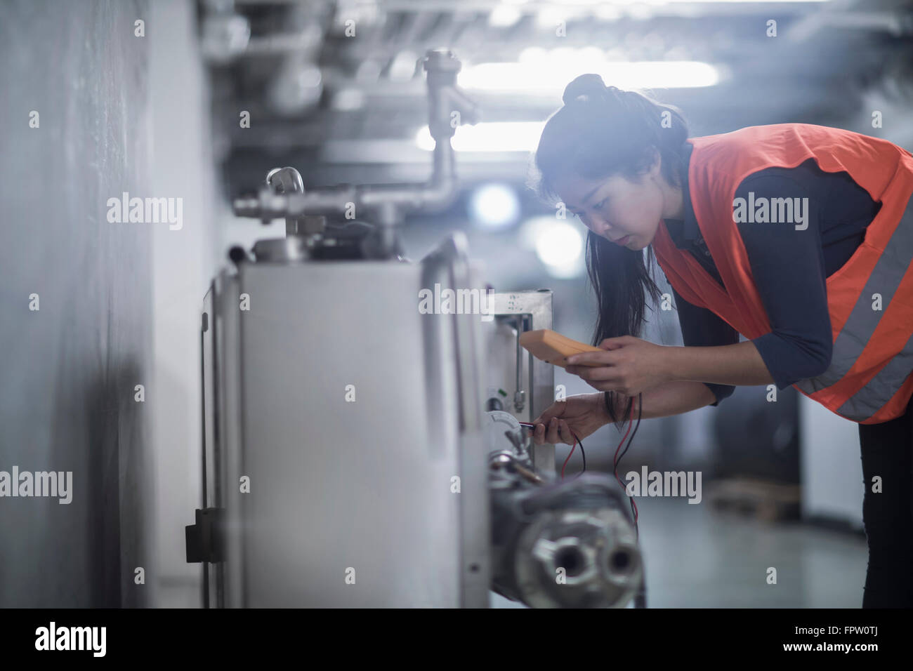 Jeune femme engineer machine avec multimètre dans une installation industrielle, Freiburg im Breisgau, Bade-Wurtemberg, Allemagne Banque D'Images