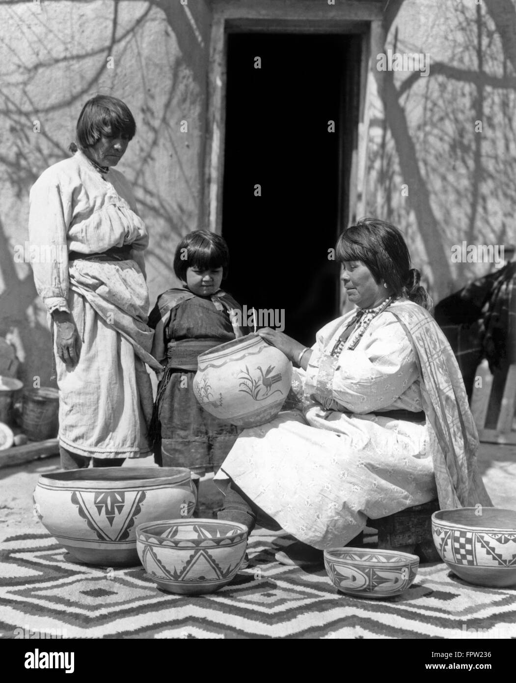 1930 PUEBLO WOMAN DECORATING POTERIE une femme plus âgée et l'ENFANT À CÔTÉ DE SUR Banque D'Images