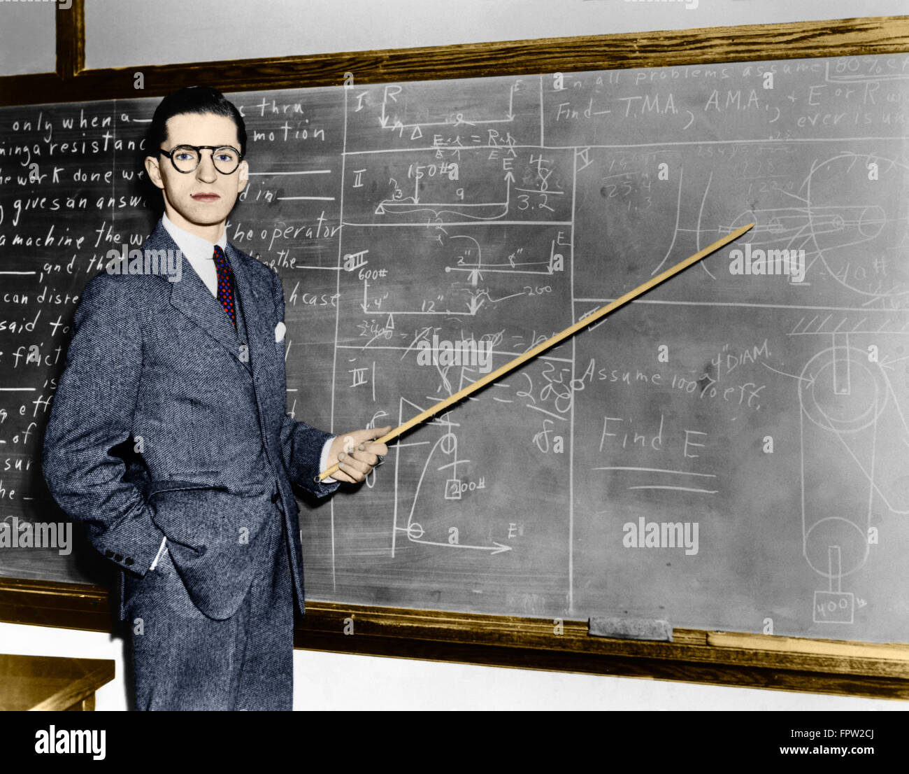 1930 1940 ENSEIGNANT HOMME POINTEUR VERS LE PROFESSEUR AT BLACKBOARD LOOKING AT CAMERA Banque D'Images