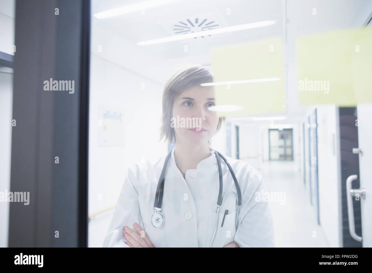 Jeune femme médecin à l'hôpital à des notes sur porte, Freiburg im Breisgau, Bade-Wurtemberg, Allemagne Banque D'Images