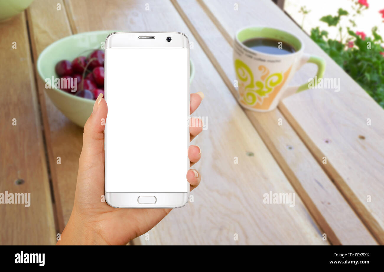 Téléphone intelligent avec affichage isolé pour une maquette en main. Le temps de vous détendre avec un café sur la table. Banque D'Images