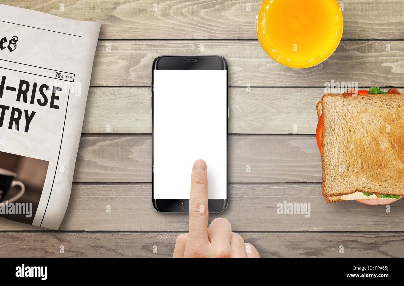 Téléphone intelligent avec affichage isolé pour une maquette. Part de toucher l'écran. Journal, jus et sandwich sur table. Vue d'en haut. Banque D'Images