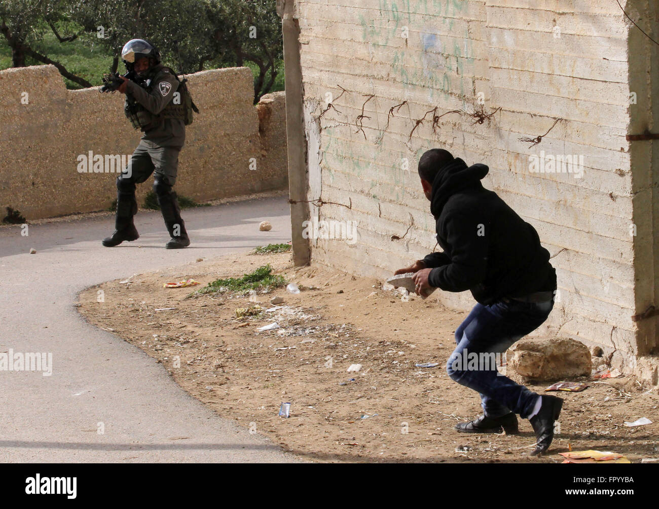 Naplouse, Cisjordanie, territoire palestinien. Mar 20, 2016. Un Palestinien lance des pierres en direction d'un membre de la sécurité israélienne dans les territoires occupés de Cisjordanie village de Douma, près de Naplouse, après l'incendie a éclaté dans les premières heures du 20 mars 2016 dans la maison appartenant à un Palestinien témoin clé d'un incendie criminel qui a eu lieu l'an dernier par des extrémistes juifs qui ont tué une famille palestinienne. Les résidents ont indiqué qu'une fenêtre était cassée dans la maison, élever les soupçons que des cocktails Molotov ont été lancés à l'intérieur -- comme cela s'est produit dans la bombe incendiaire pour juillet. Les autorités israéliennes sont en train d'enquêter sur th Banque D'Images
