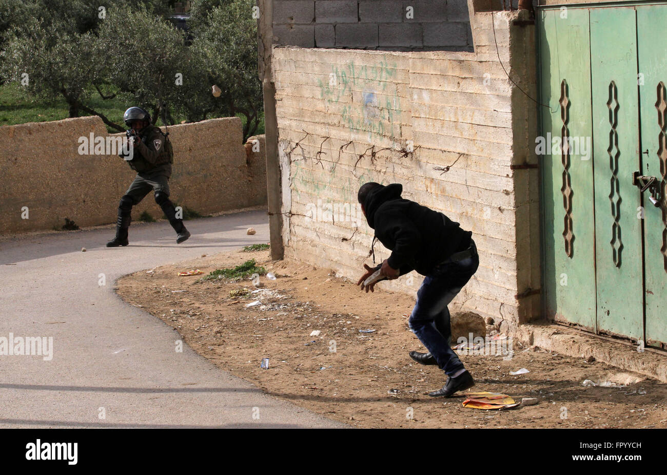 Naplouse, Cisjordanie, territoire palestinien. Mar 20, 2016. Un Palestinien lance des pierres en direction d'un membre de la sécurité israélienne dans les territoires occupés de Cisjordanie village de Douma, près de Naplouse, après l'incendie a éclaté dans les premières heures du 20 mars 2016 dans la maison appartenant à un Palestinien témoin clé d'un incendie criminel qui a eu lieu l'an dernier par des extrémistes juifs qui ont tué une famille palestinienne. Les résidents ont indiqué qu'une fenêtre était cassée dans la maison, élever les soupçons que des cocktails Molotov ont été lancés à l'intérieur -- comme cela s'est produit dans la bombe incendiaire pour juillet. Les autorités israéliennes sont en train d'enquêter sur th Banque D'Images