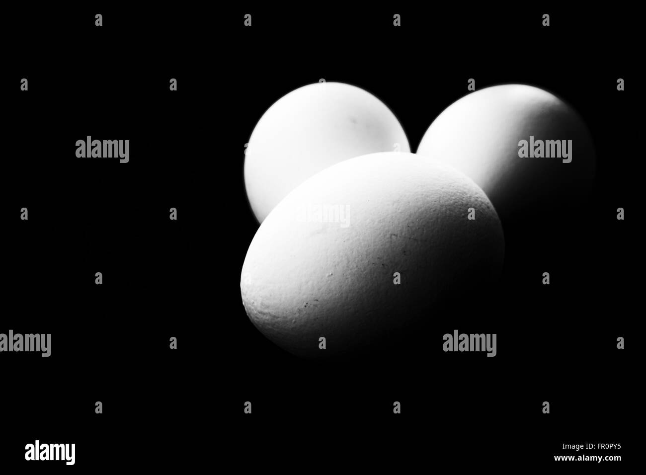 Trois oeufs contre un fond noir foncé avec copyspace domaine. Banque D'Images