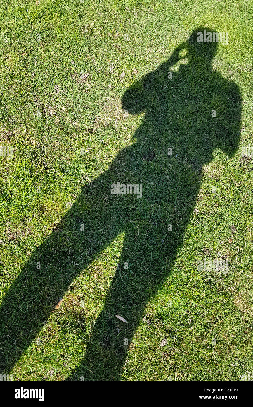 Le stress, les maux de tête, soins de santé et les personnes concept : l'ombre de l'homme projetée sur l'herbe verte avec la main à sa tête Banque D'Images
