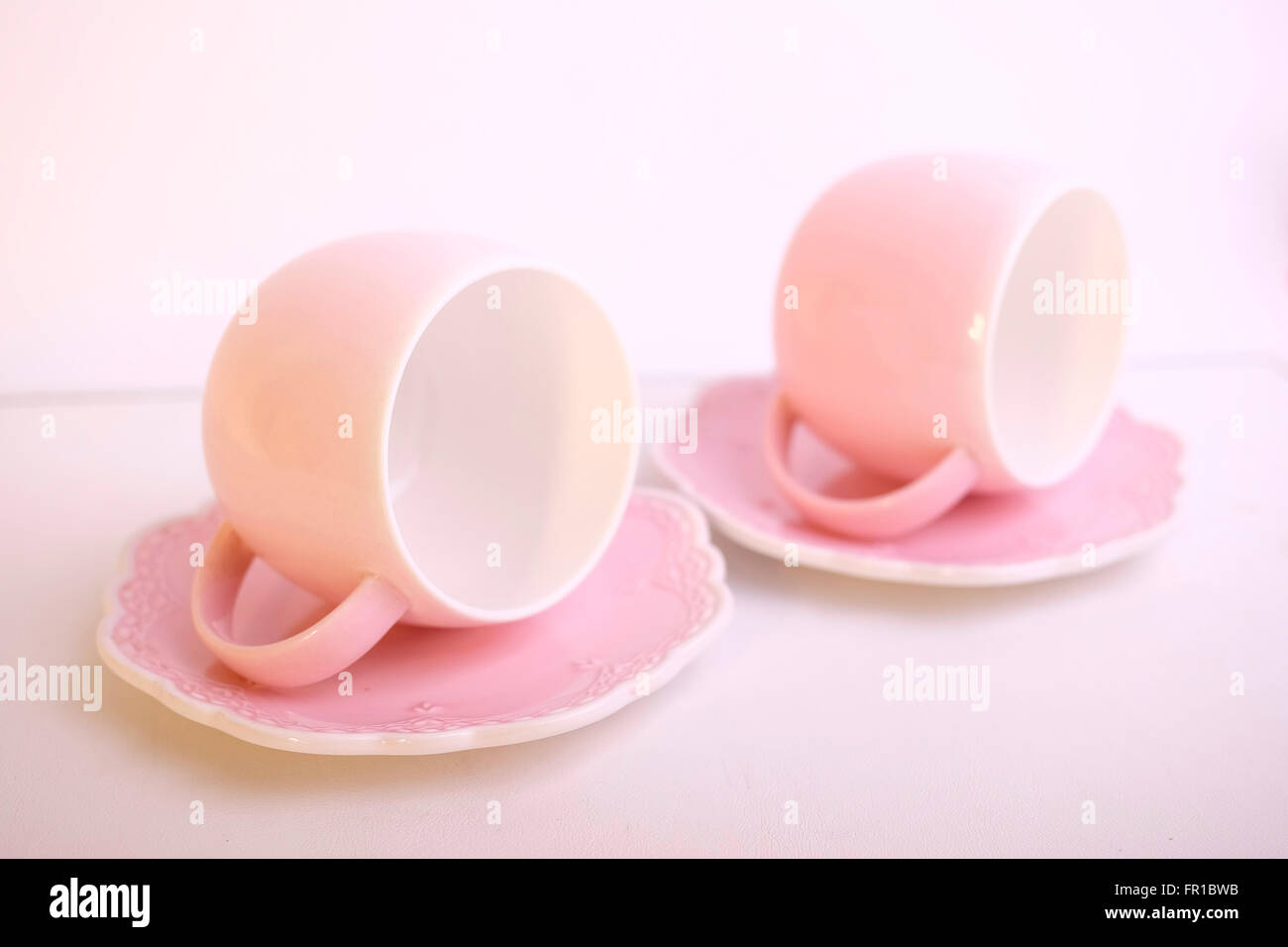 Deux tasses en céramique rose délicates assorties avec des intérieurs blancs et des soucoupes décoratives créant une esthétique douce et féminine, évoquant des concepts de l'heure du thé Banque D'Images