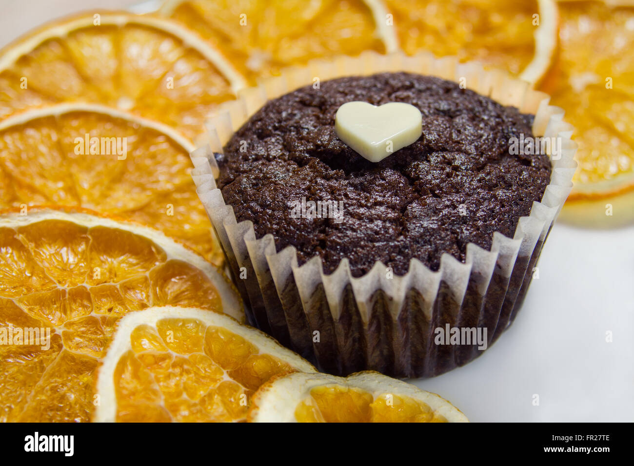 Muffin au chocolat avec des tranches d'orange séchée sur plaque blanche. Banque D'Images
