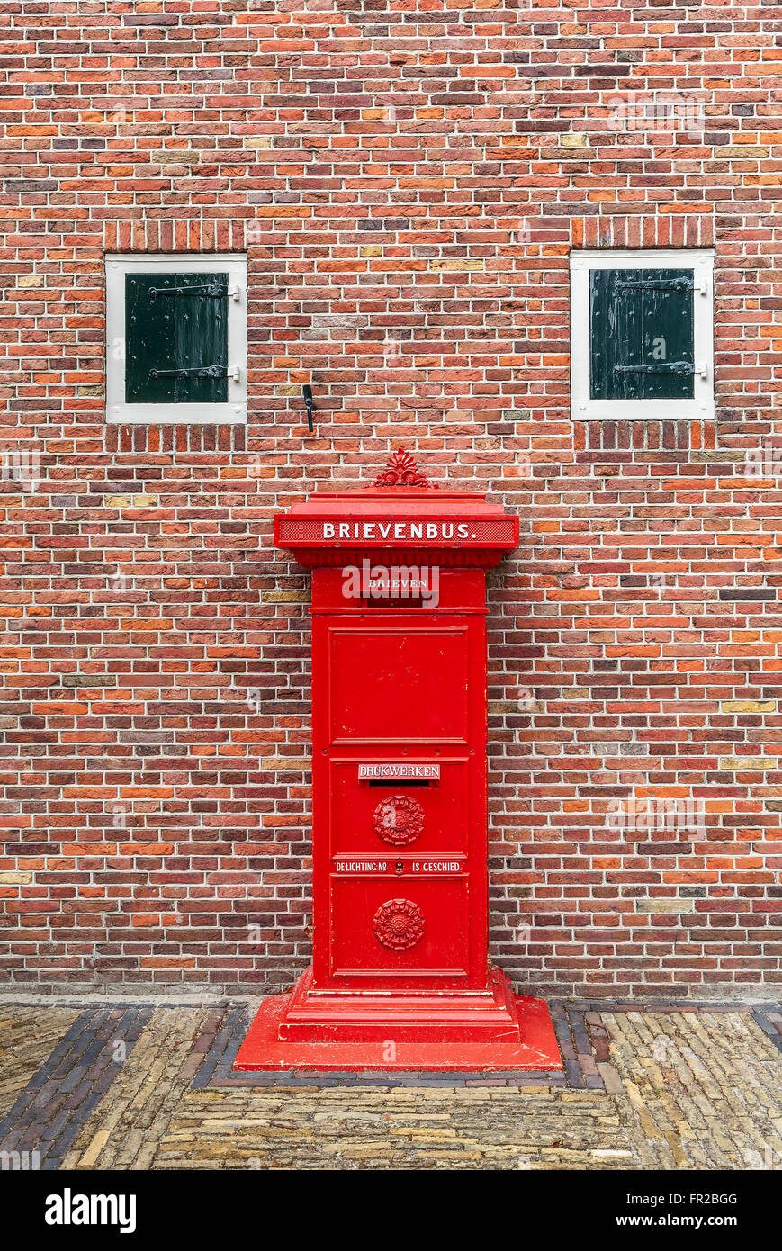 Ancienne boite aux lettres rouge en face de mur de brique à Zaanse, Pays-Bas. Banque D'Images