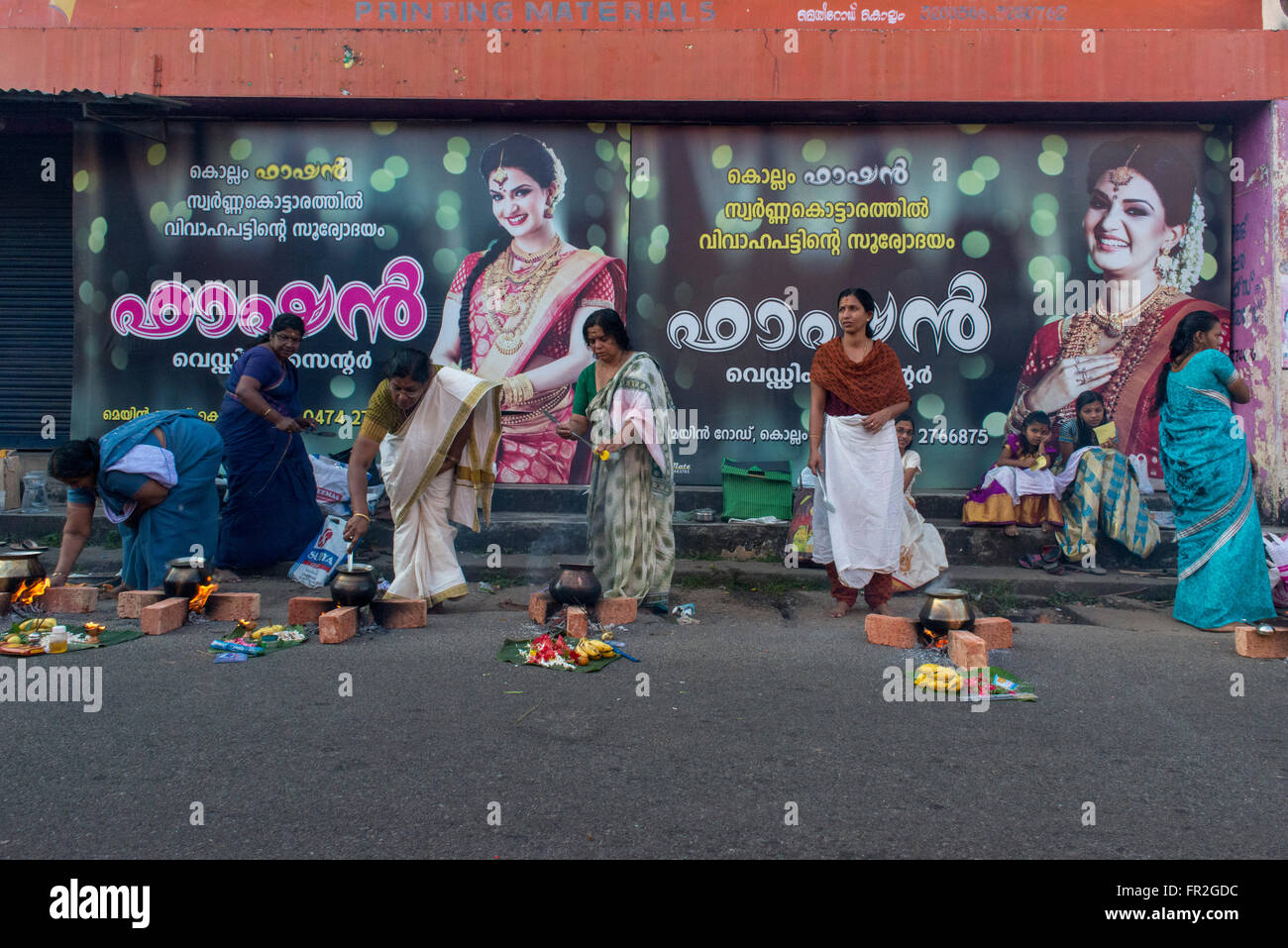 Mesdames la cuisson dans la rue pour l'Hindu Cérémonie devant l'affiche de film, Kollam Banque D'Images