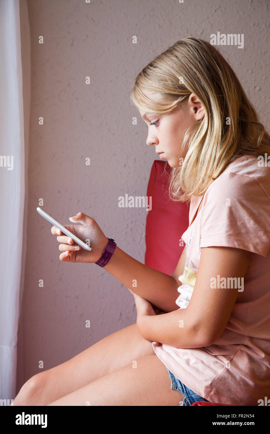 Cute Young blonde woman in pink t-shirt à l'aide de la messagerie pour smartphone, portrait de profil Banque D'Images