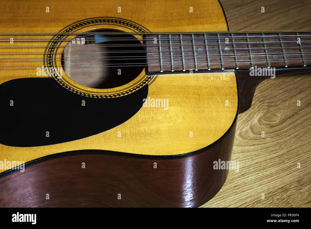 Partie du corps de guitare 12 cordes jaune allongé sur le plancher en bois libre Banque D'Images