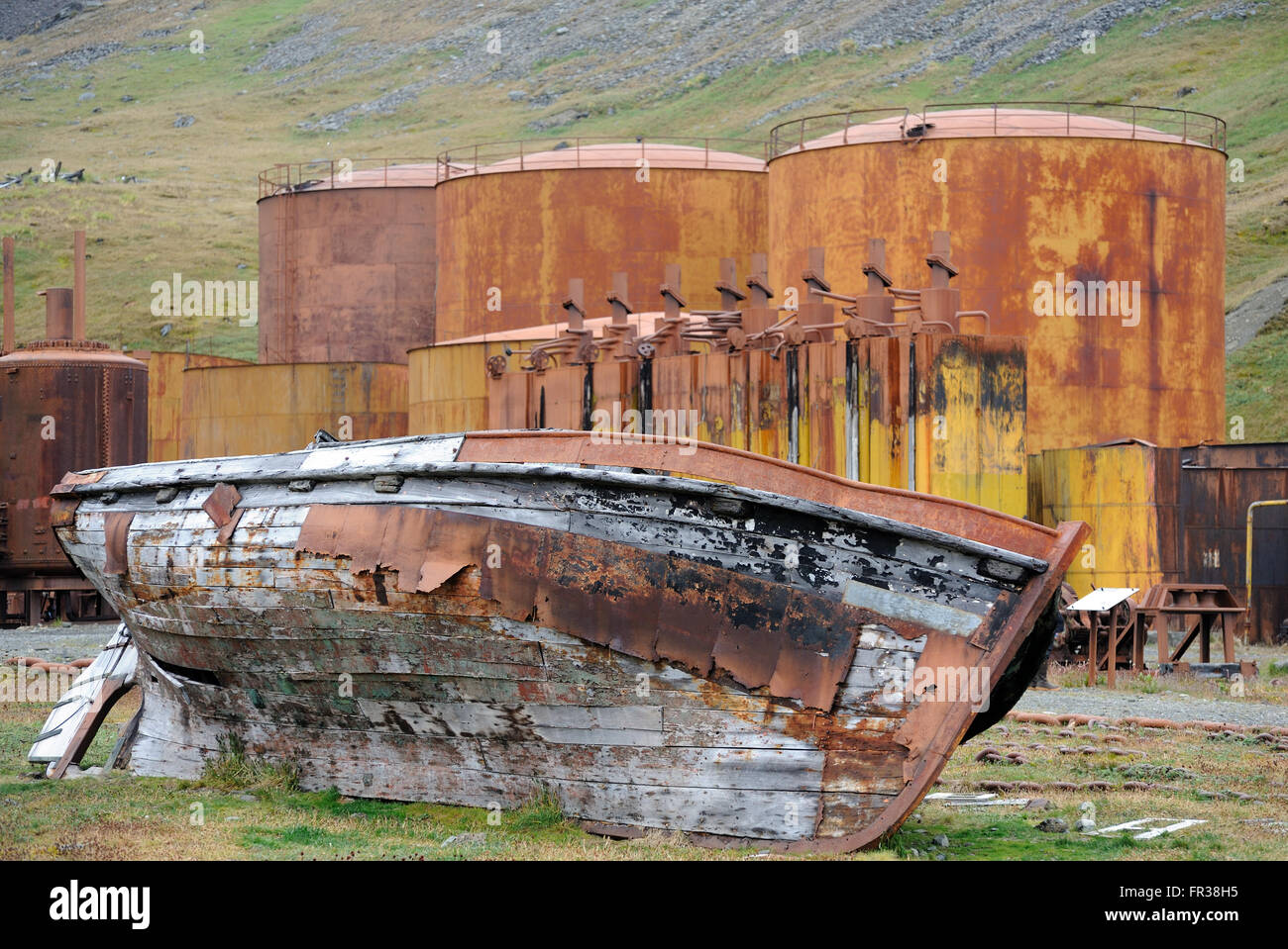 Un bateau pourrit parmi la rouille des réservoirs pour le stockage de l'huile de phoque et de baleine dans la station baleinière. Grytviken, Géorgie du Sud Banque D'Images