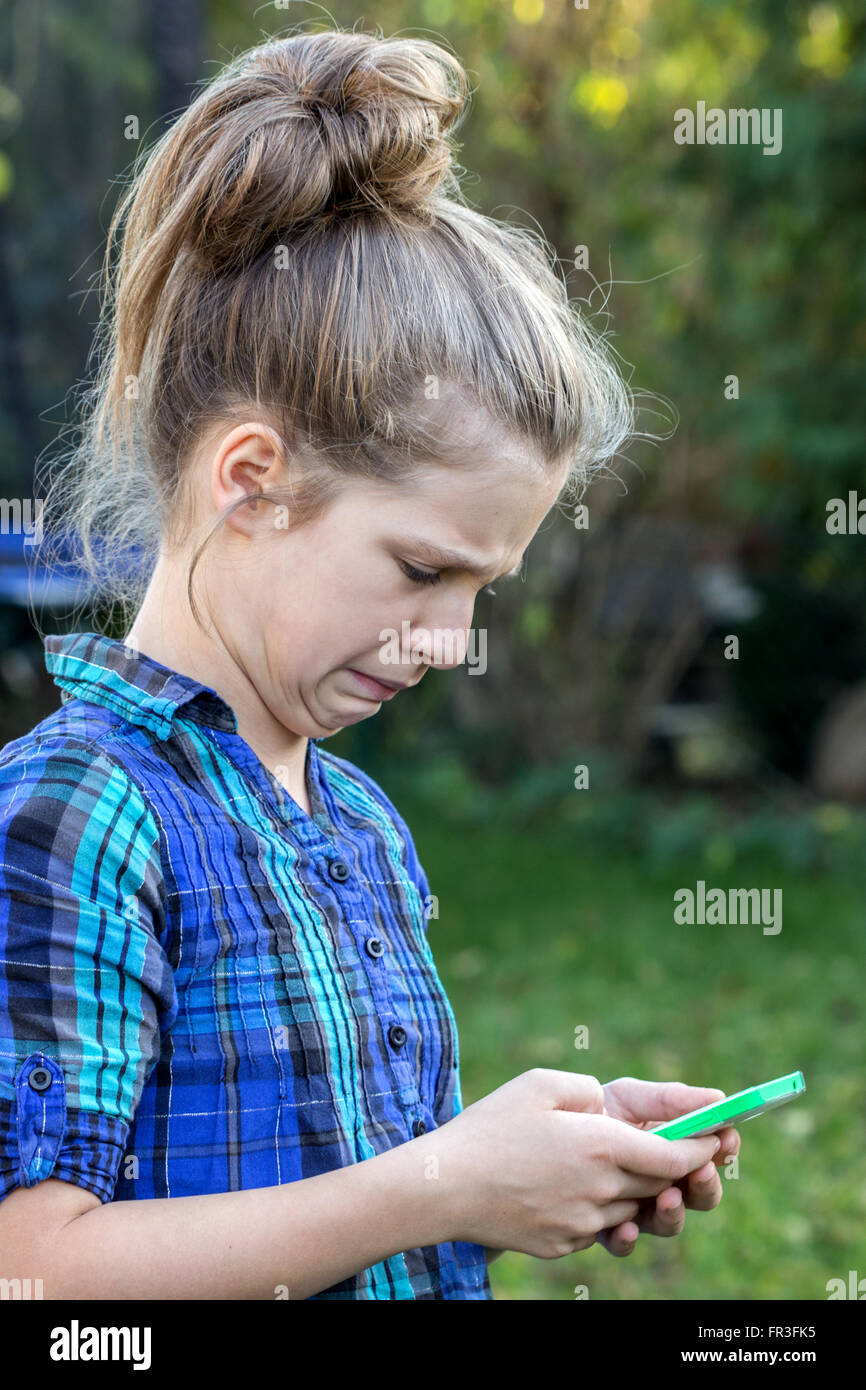 Une jeune fille regarde son téléphone cellulaire dans le dégoût Banque D'Images