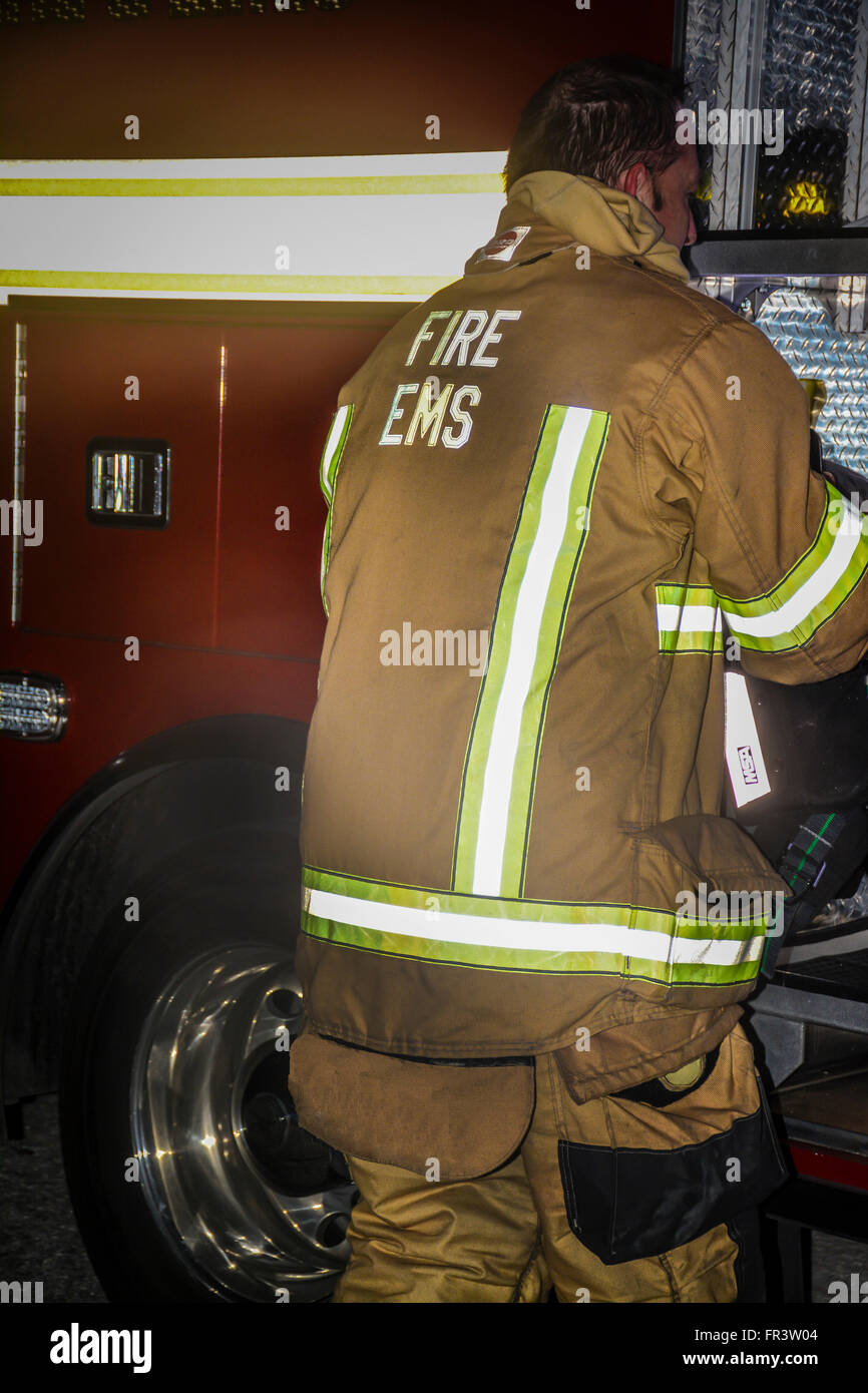 Un pompier en uniforme fonctionne pendant une situation d'urgence avec son camion EMS au cours d'une situation de nuit Banque D'Images