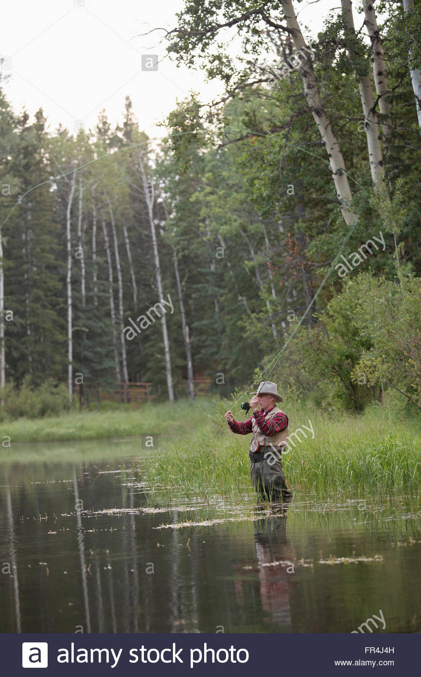 Homme d'âge moyen casting sa mouche canne à pêche Banque D'Images