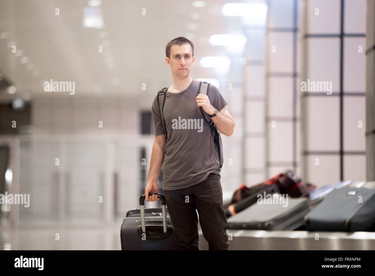 Portrait de jeune homme en voyageur beau 20s salon Arrivée Départ de l'aérogare après avoir recueilli ses baggag Banque D'Images