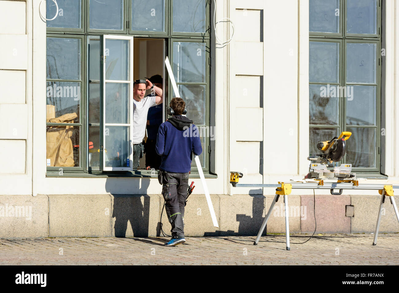 Kalmar, Suède - Mars 17, 2016 : un jeune adulte à l'extérieur de la fenêtre Gérer une scie à onglets et remettre les planches sciées t Banque D'Images