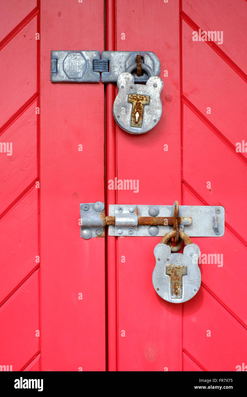 Des cadenas sur les portes en bois peint rouge lumineuse uk Banque D'Images