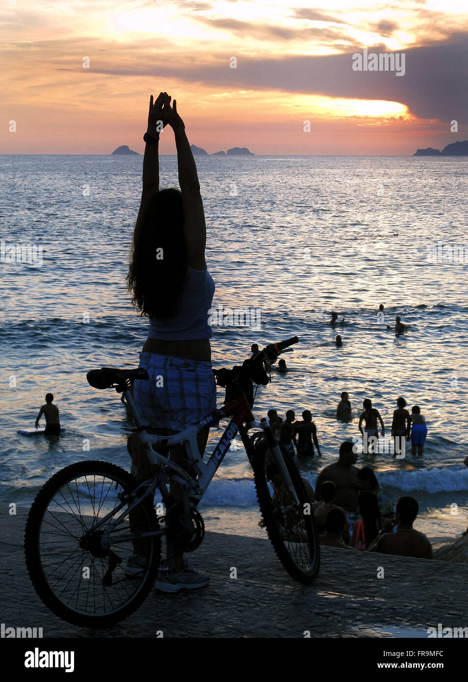 Cycliste en regardant le coucher de soleil à la plage de l'Arpoador à Ipanema Banque D'Images