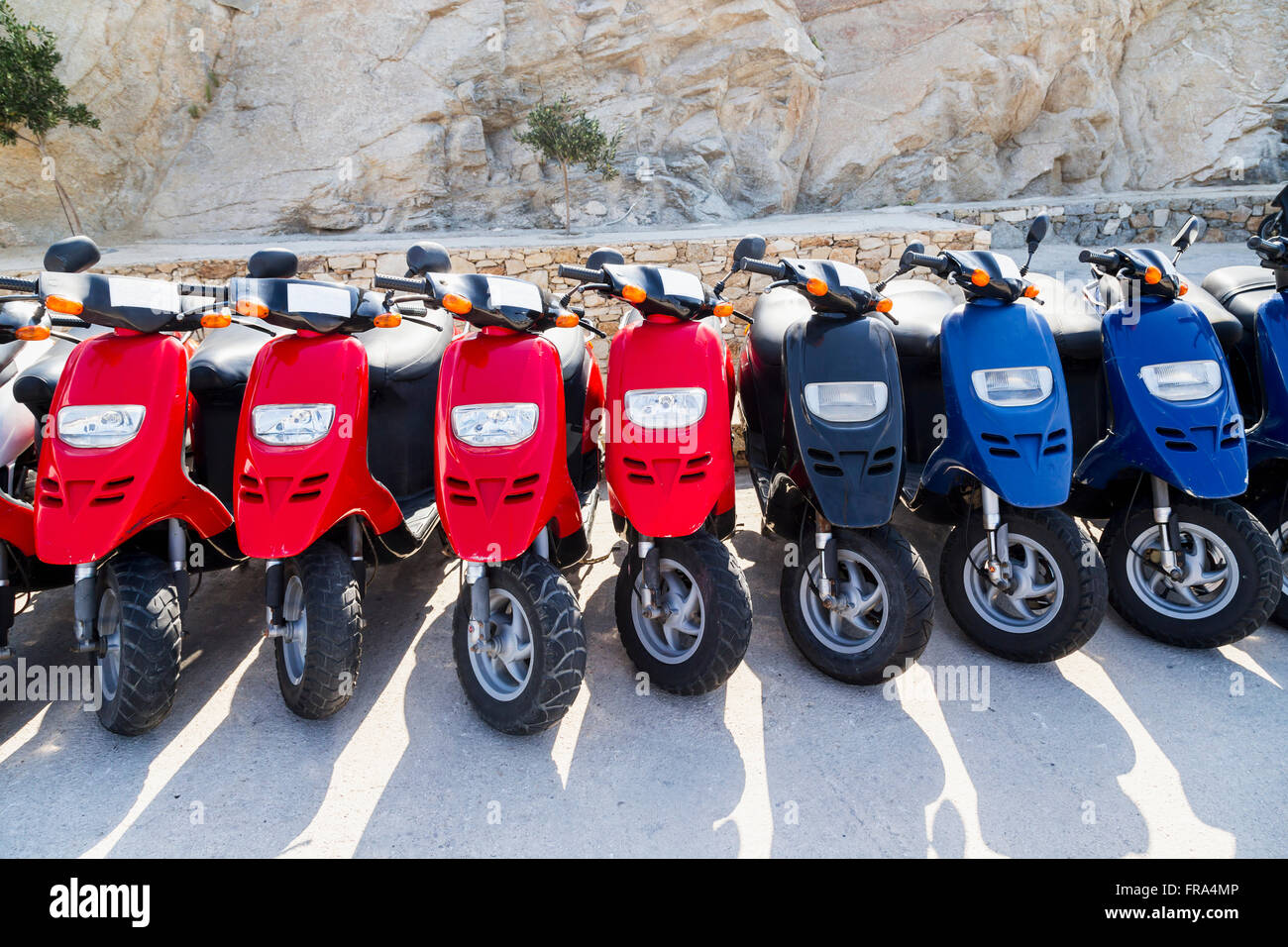 Une ligne colorée de scooters la queue à une agence de location à côté du  port de navires de croisière pour les touristes à louer ; île de Mykonos,  îles grecques, Grèce