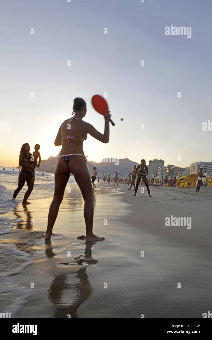 Femme jouant de racquetball au coucher du soleil sur la plage d'Ipanema Banque D'Images