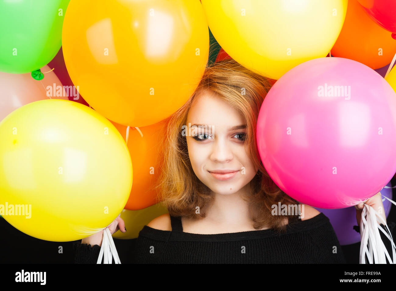 Studio portrait of happy smiling young Caucasian blonde avec des ballons colorés Banque D'Images
