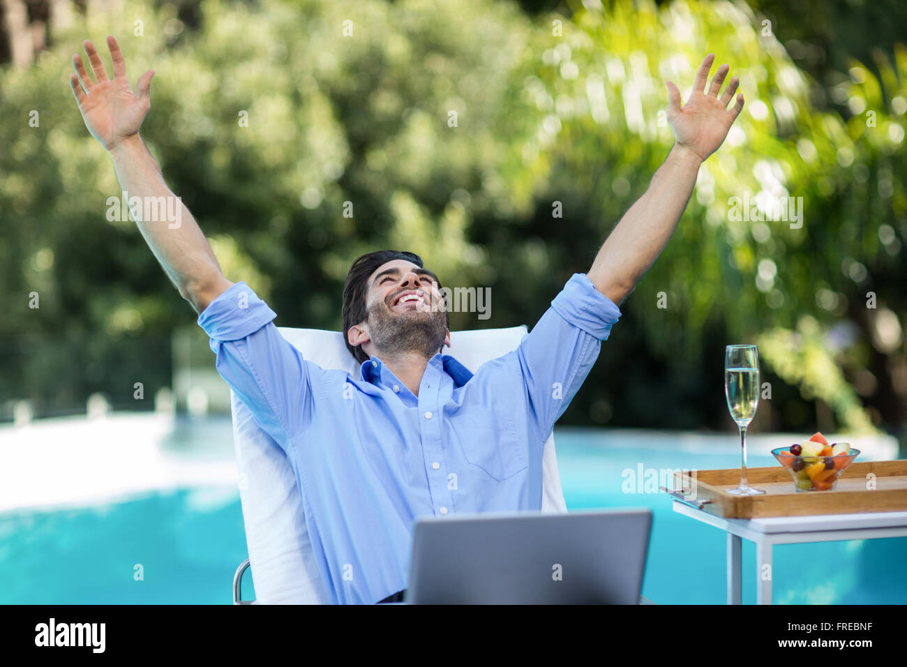 L'homme excité à l'aide d'un ordinateur portable près de la piscine Banque D'Images