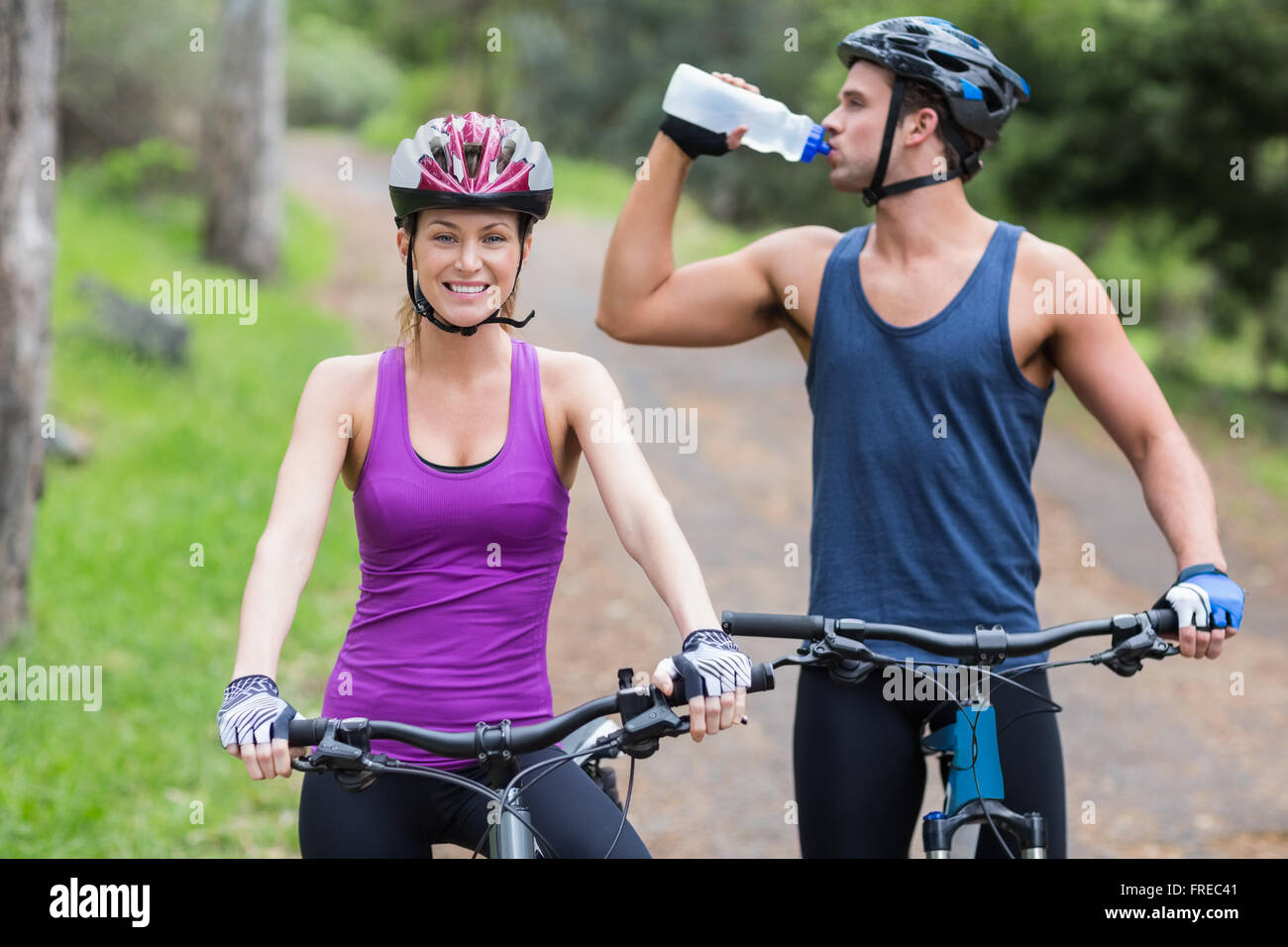 L'eau potable de motards par femme en forêt Banque D'Images