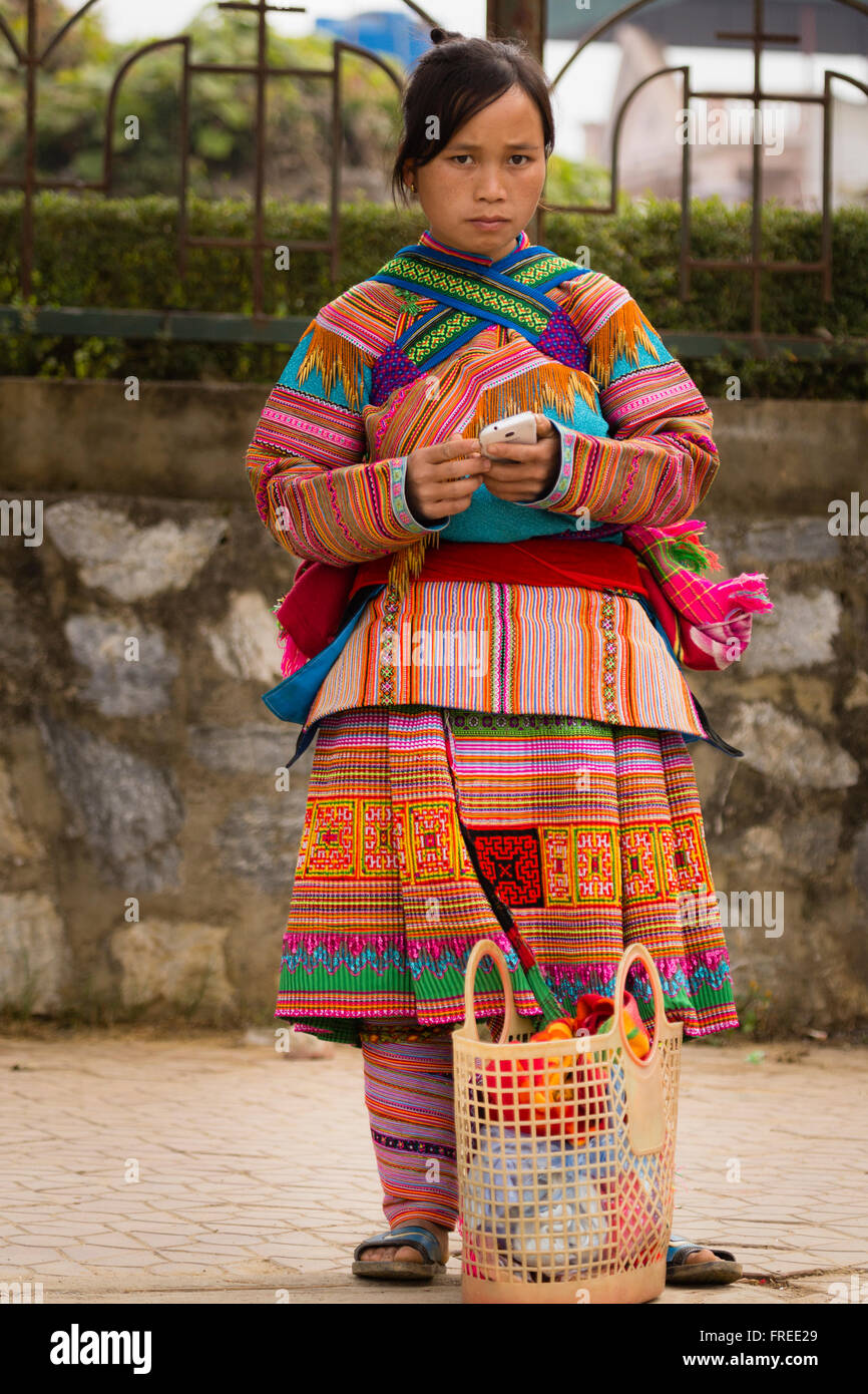 Femme en costume traditionnel coloré avec un smartphone, Bac Ha, Nord, Vietnam Banque D'Images