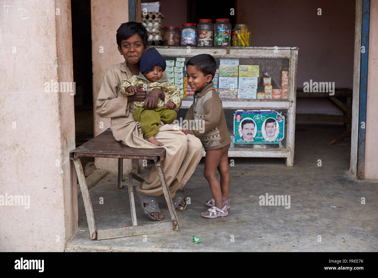 Des enfants assis en face d'une petite boutique, Mahey, Pakistan Banque D'Images