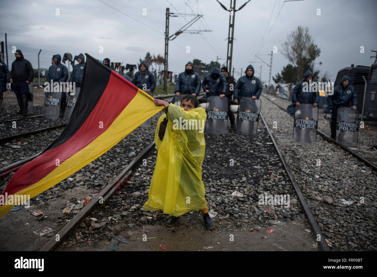 Un garçon est titulaire d'un drapeau allemand et montre en face de la police ; les réfugiés et migrants échoués protester contre la frontière de la Macédoine grecque, exigeant pour les frontières d'ouvrir, afin de continuer leur voyage vers le nord de l'Europe du nord, près du village grec de Idomeni Banque D'Images