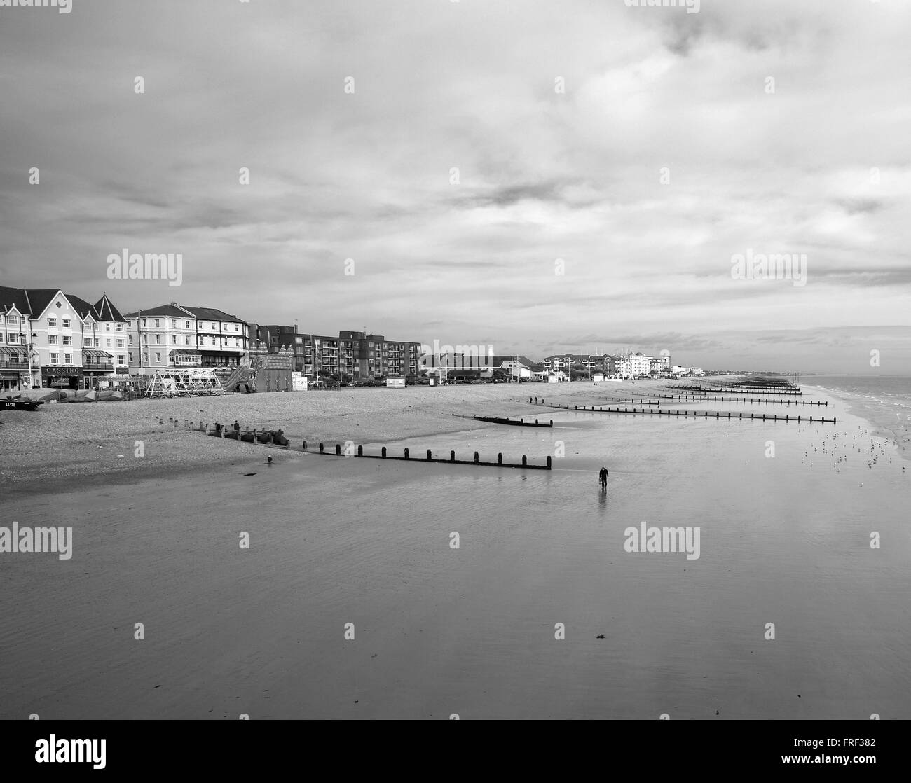 Front de mer et de la plage de Bognor Regis avec lonely walker en noir et blanc Banque D'Images