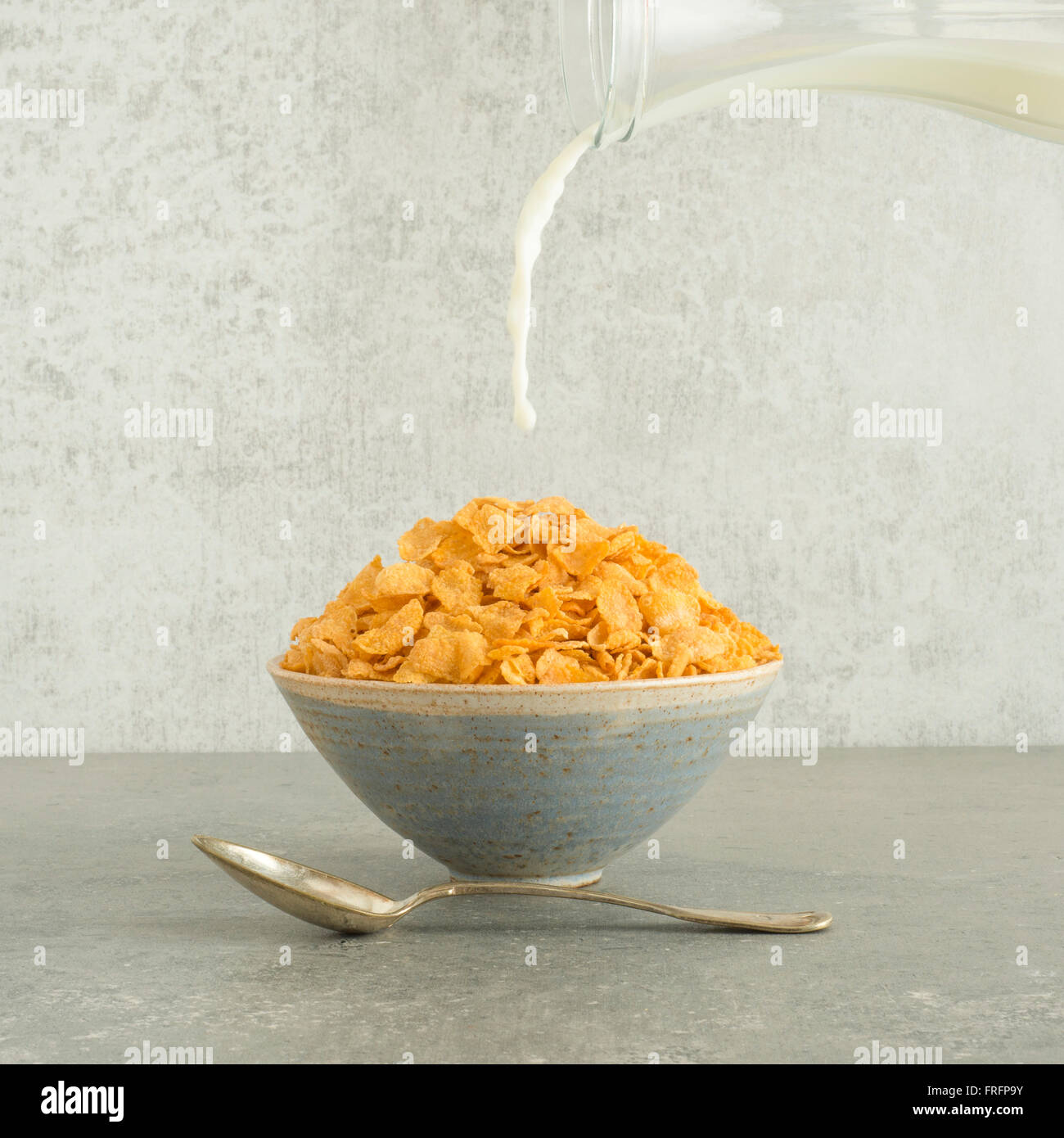 Verser le lait sur les flocons dans un bol de petit-déjeuner. La vie toujours des aliments. Concept de la saine alimentation et les habitudes du matin. Banque D'Images