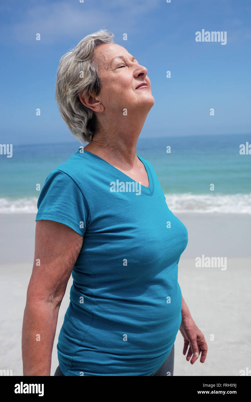 Senior woman with eyes closed debout sur la plage Banque D'Images
