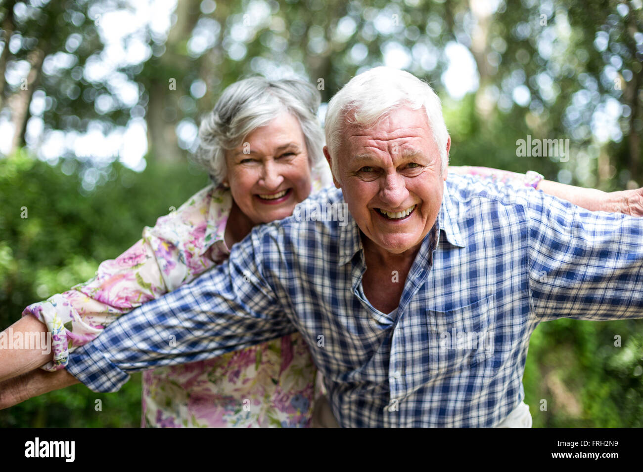 Happy senior couple with arms outstretched en cour arrière Banque D'Images