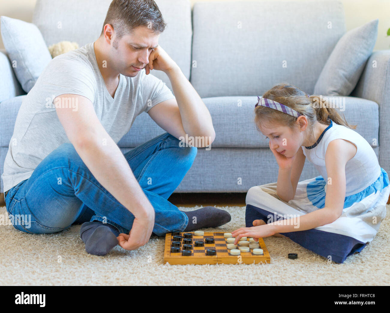 Petite fille et son père jouer aux dames. Banque D'Images