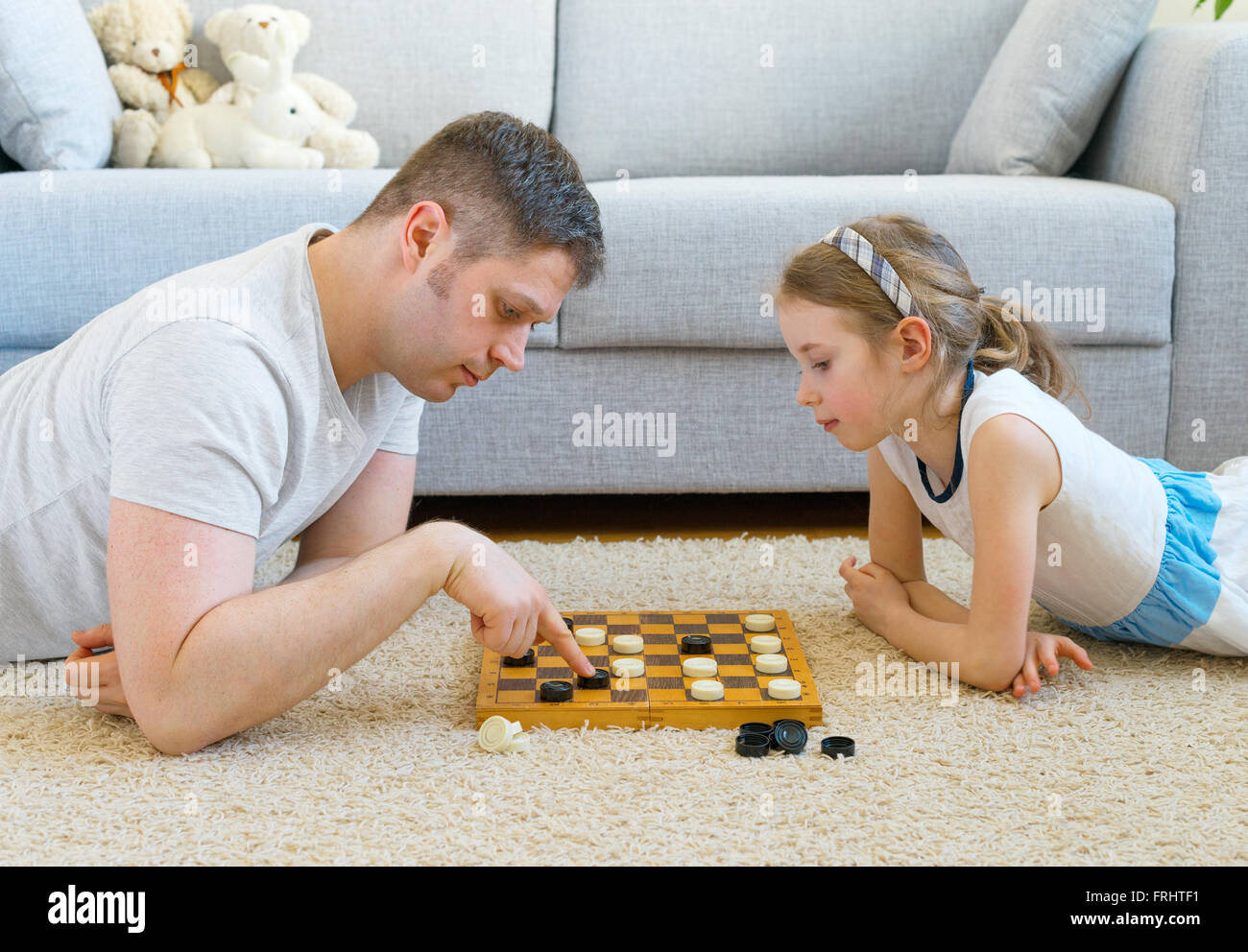 Petite fille et son père jouer aux dames. Banque D'Images