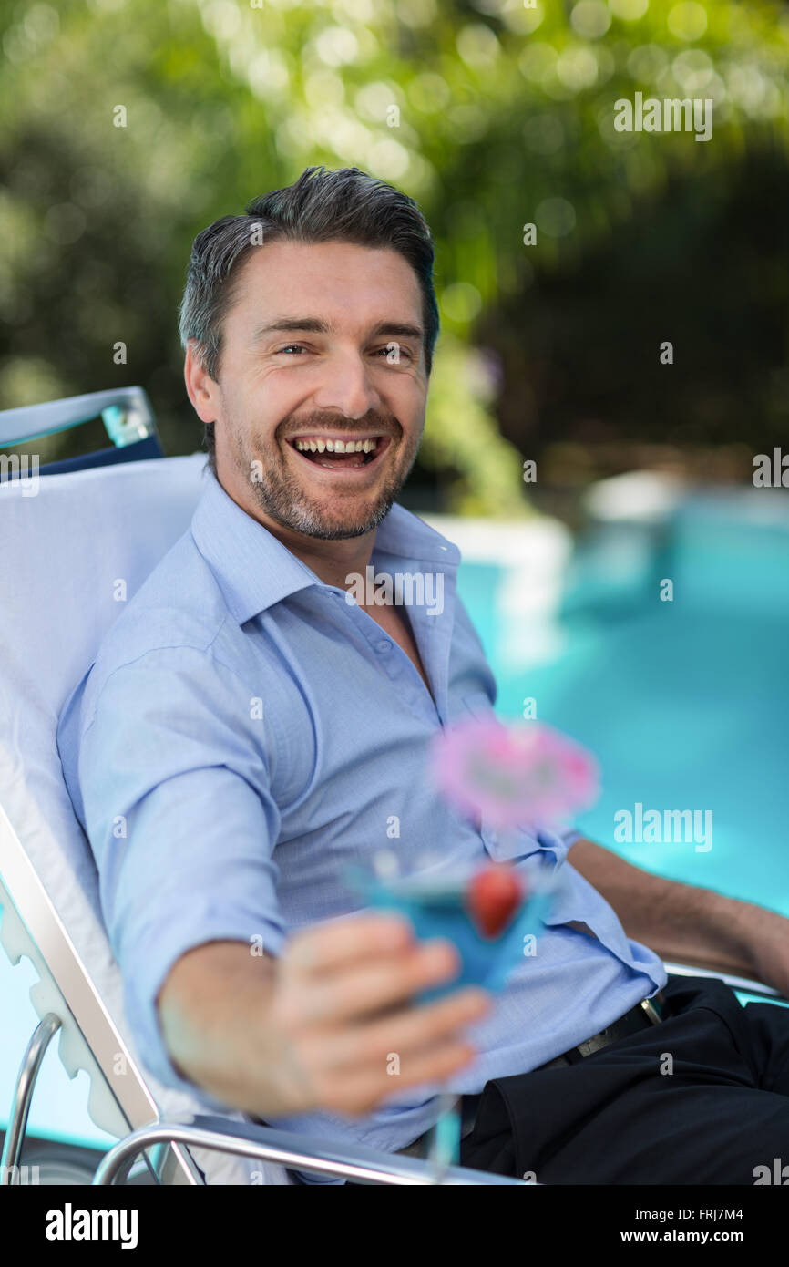 Smart homme tenant un verre à martini tout en vous relaxant dans une chaise longue Banque D'Images